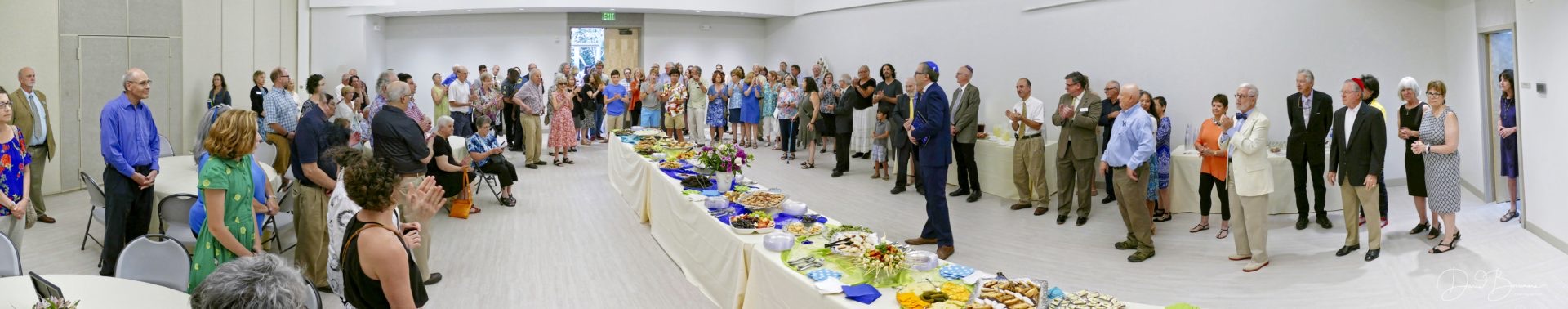 The congregation gathered around a long buffet table at an oneg